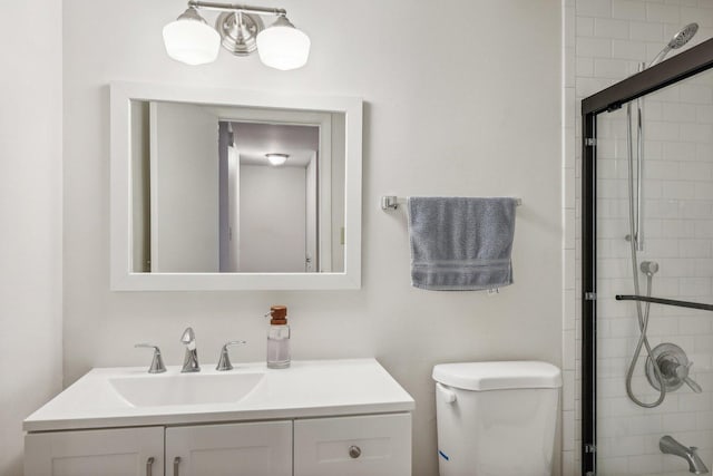 bathroom featuring vanity, toilet, and a shower with shower door