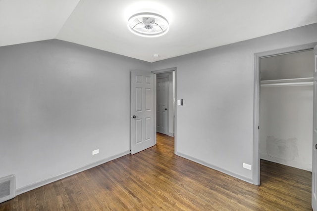 unfurnished bedroom with dark hardwood / wood-style floors, lofted ceiling, and a closet