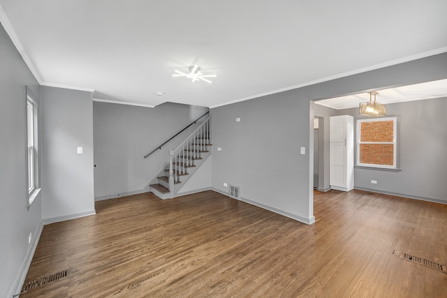 unfurnished living room featuring a chandelier, hardwood / wood-style flooring, and ornamental molding