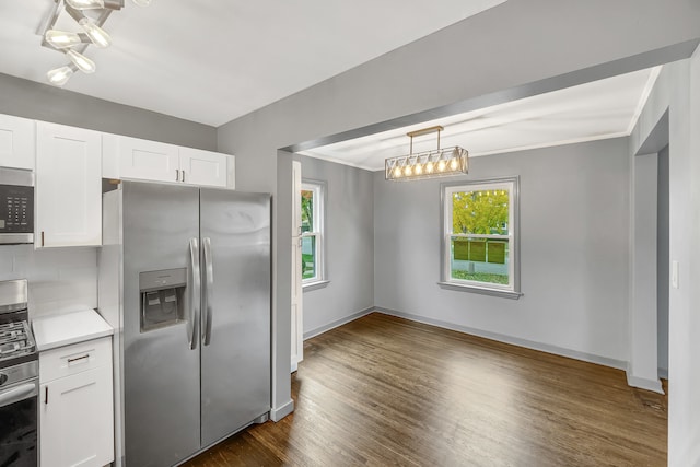 kitchen with stainless steel appliances, crown molding, pendant lighting, dark hardwood / wood-style floors, and white cabinetry