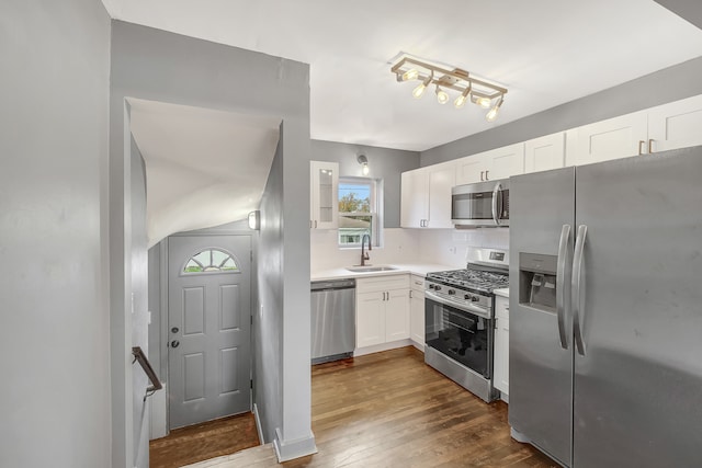 kitchen featuring sink, hardwood / wood-style flooring, decorative backsplash, white cabinetry, and stainless steel appliances