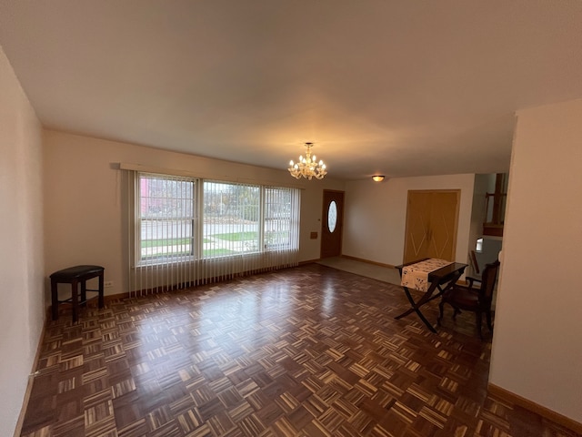 unfurnished living room featuring dark parquet floors and an inviting chandelier