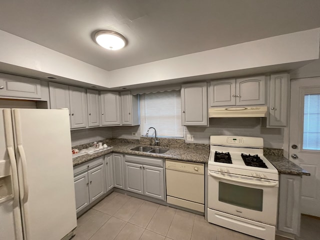 kitchen featuring gray cabinetry, sink, dark stone countertops, white appliances, and light tile patterned floors