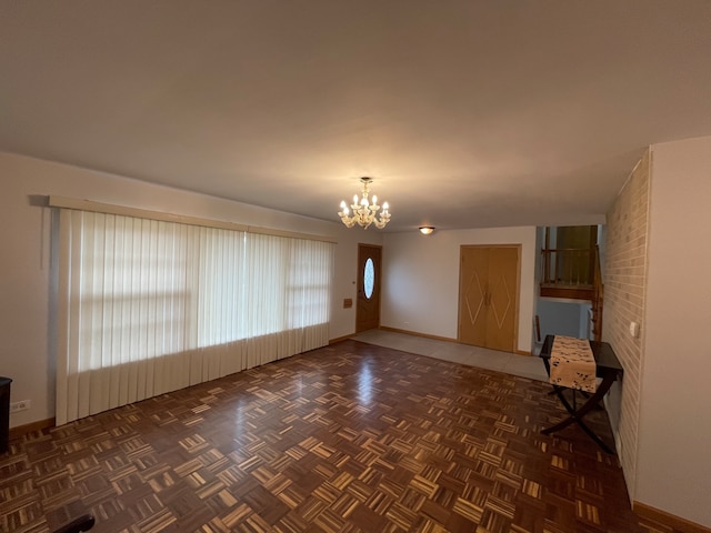 unfurnished living room with dark parquet floors and a chandelier