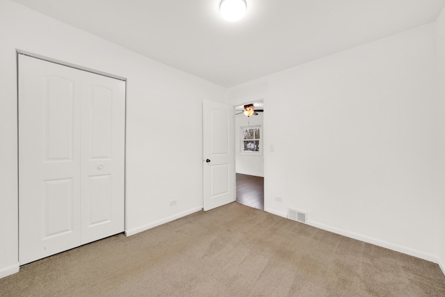 unfurnished bedroom featuring light colored carpet and a closet