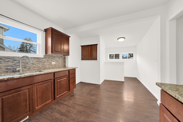 kitchen with light stone countertops, dark hardwood / wood-style floors, tasteful backsplash, and sink