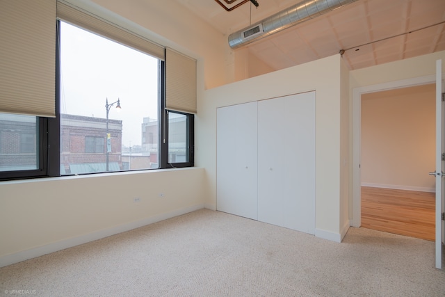 unfurnished bedroom featuring light colored carpet and a closet