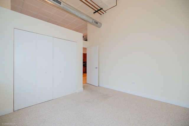 unfurnished bedroom featuring a closet and light colored carpet