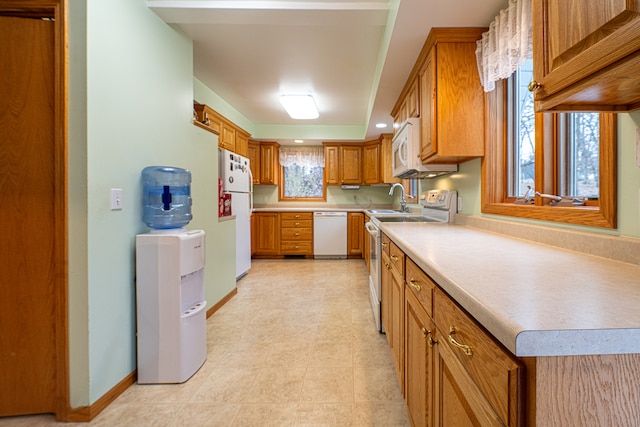 kitchen with white appliances, a healthy amount of sunlight, and sink