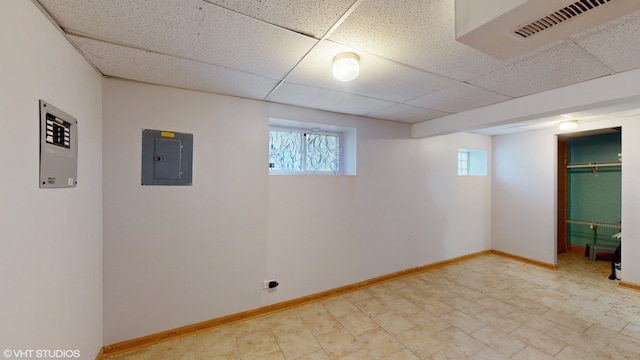 basement with a drop ceiling and electric panel