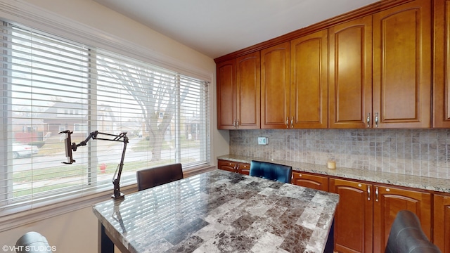 kitchen with backsplash, a wealth of natural light, and light stone counters