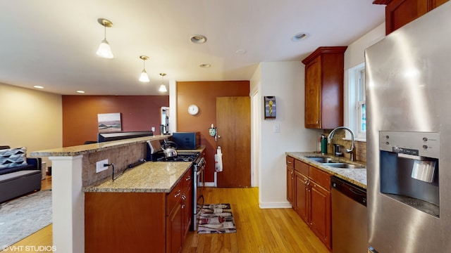 kitchen featuring pendant lighting, backsplash, sink, light hardwood / wood-style flooring, and appliances with stainless steel finishes