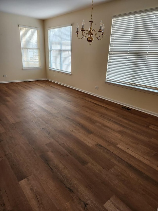 unfurnished room with dark wood-type flooring and an inviting chandelier