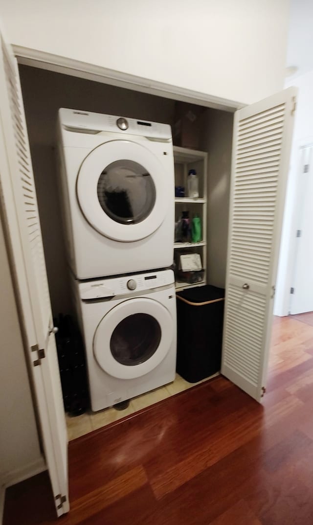 laundry room featuring dark hardwood / wood-style floors and stacked washer and clothes dryer