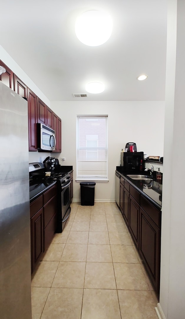 kitchen featuring appliances with stainless steel finishes, light tile patterned floors, and sink