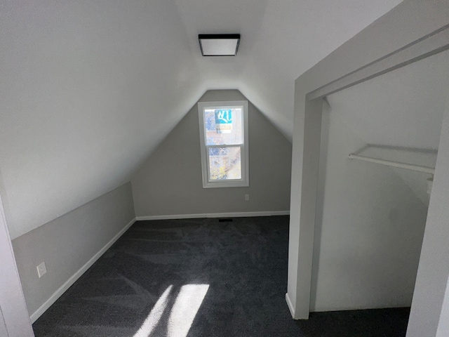 bonus room with dark colored carpet and lofted ceiling