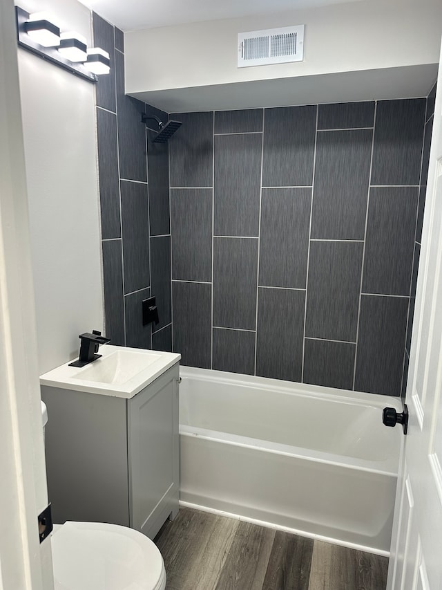 full bathroom featuring vanity, hardwood / wood-style flooring, toilet, and tiled shower / bath