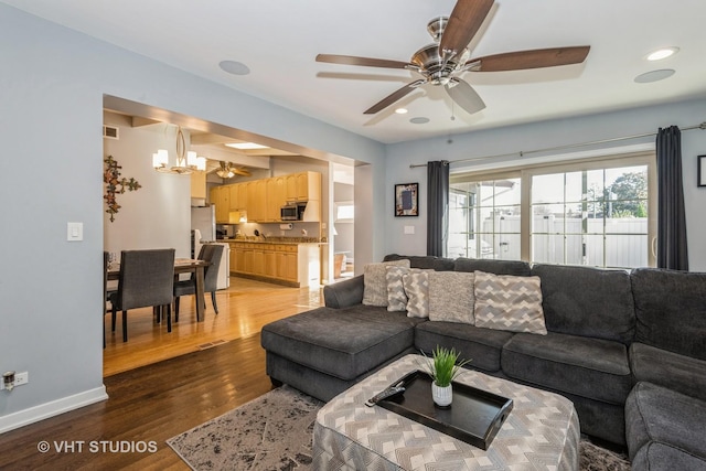 living room featuring ceiling fan with notable chandelier and hardwood / wood-style floors