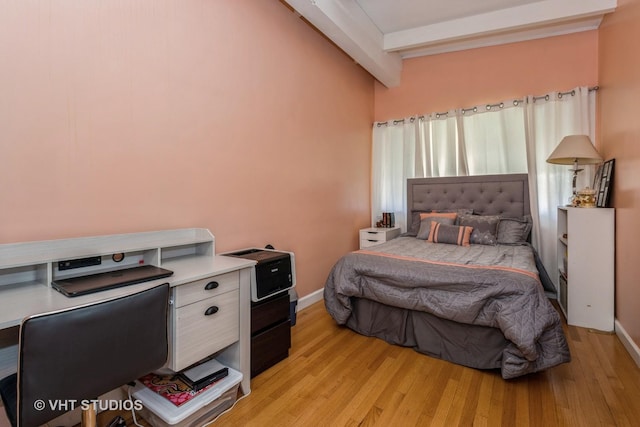 bedroom featuring light hardwood / wood-style floors and beamed ceiling