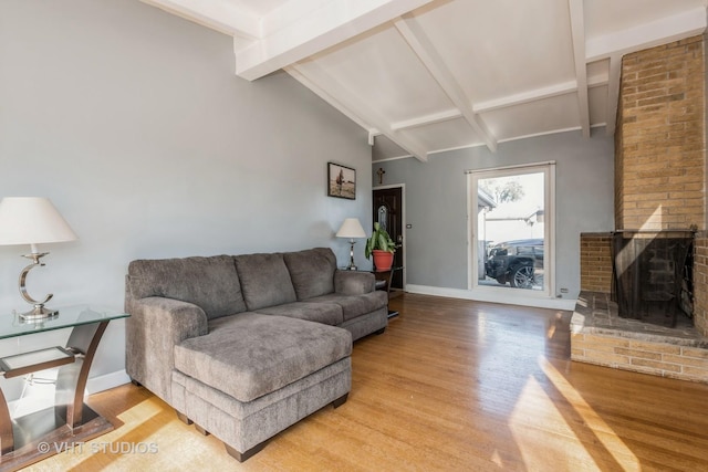 living room with vaulted ceiling with beams, a fireplace, and light hardwood / wood-style floors