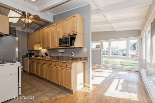 kitchen with light brown cabinets, stainless steel appliances, lofted ceiling with beams, ceiling fan, and light stone counters