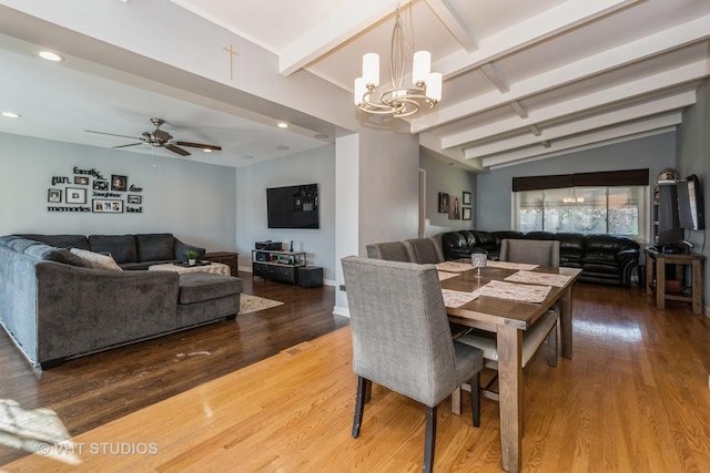 dining space with ceiling fan with notable chandelier, hardwood / wood-style flooring, and lofted ceiling with beams