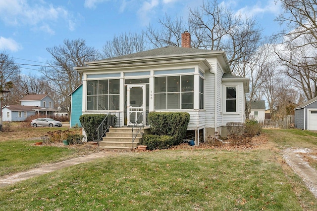 view of front of house with a front yard and a sunroom