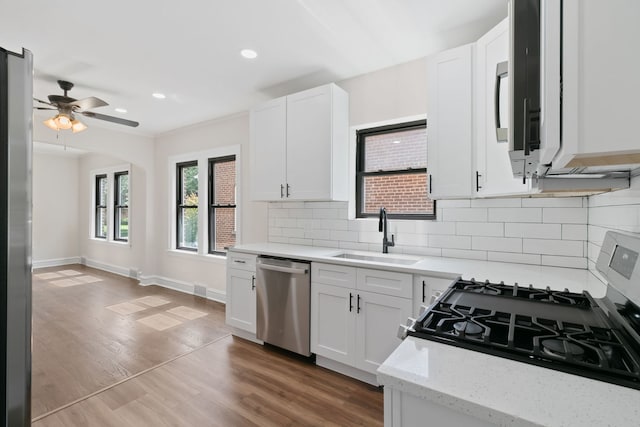 kitchen with gas stove, white cabinetry, sink, and stainless steel dishwasher