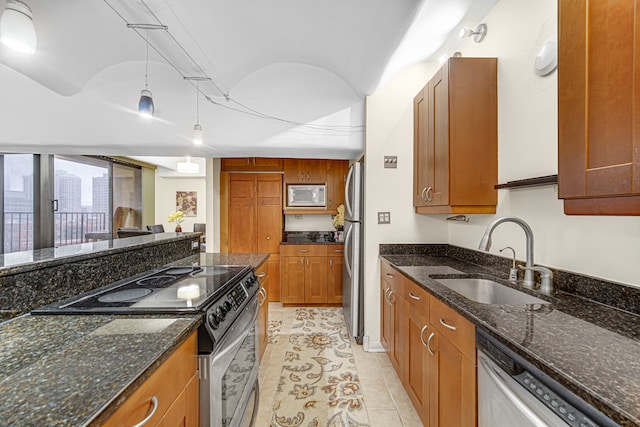 kitchen featuring decorative light fixtures, dark stone countertops, sink, and appliances with stainless steel finishes