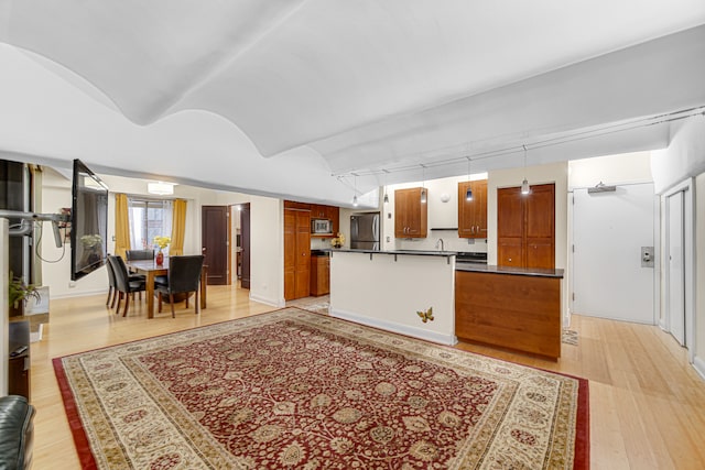 kitchen featuring hanging light fixtures, stainless steel appliances, track lighting, and light hardwood / wood-style floors