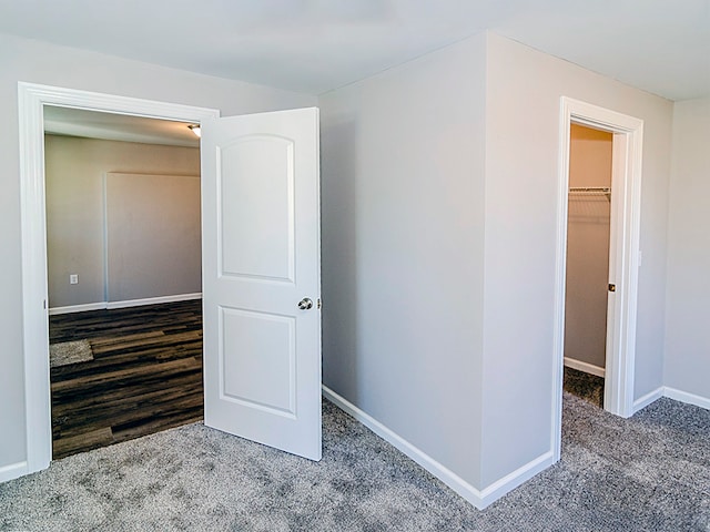 unfurnished bedroom featuring a walk in closet, hardwood / wood-style flooring, and a closet