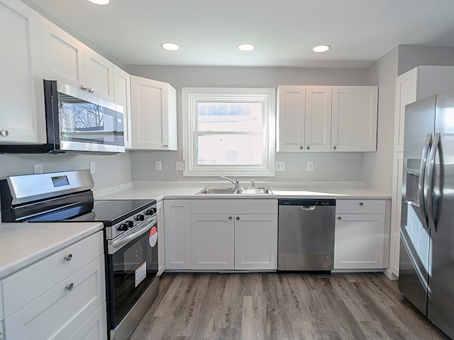 kitchen featuring white cabinetry, sink, stainless steel appliances, and wood-type flooring