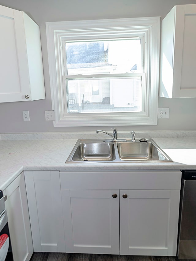 kitchen featuring stainless steel dishwasher, white cabinetry, and sink