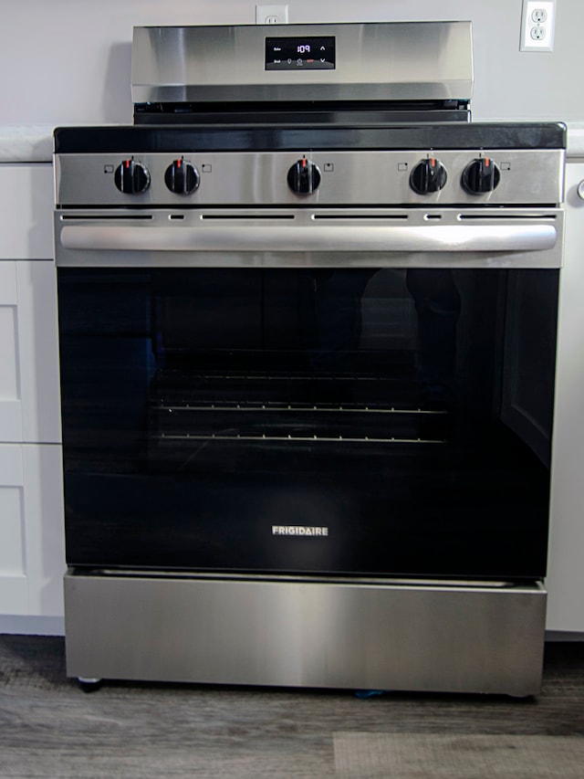 room details featuring dark hardwood / wood-style flooring, white cabinetry, and stainless steel range oven