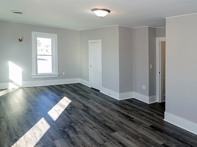 unfurnished room featuring ornamental molding and dark wood-type flooring