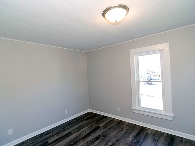 empty room with dark hardwood / wood-style floors and crown molding