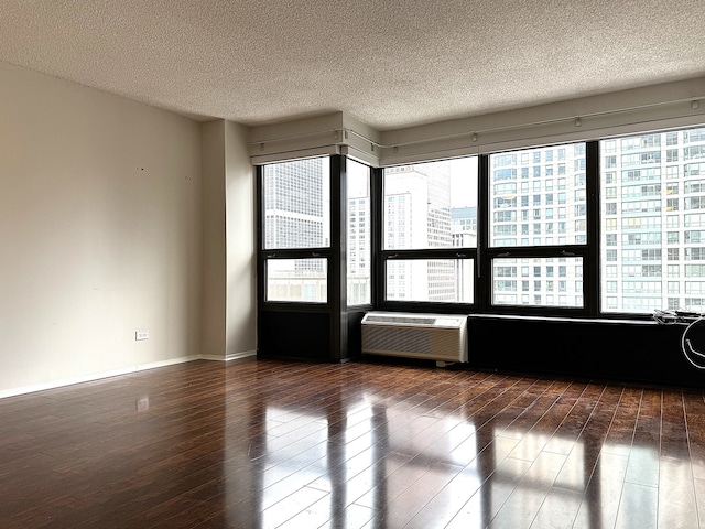 spare room featuring a textured ceiling, dark hardwood / wood-style flooring, and a wall unit AC