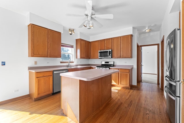 kitchen featuring stainless steel appliances, light countertops, a sink, and light wood finished floors