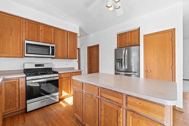 kitchen with appliances with stainless steel finishes, wood finished floors, and brown cabinets