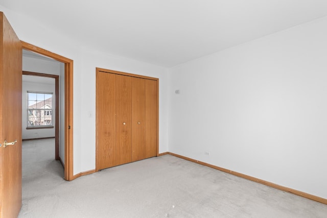 unfurnished bedroom featuring light carpet, a closet, and baseboards