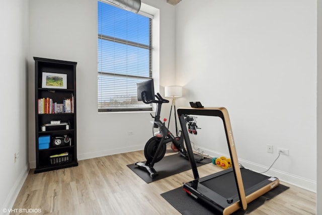 exercise room with baseboards and wood finished floors