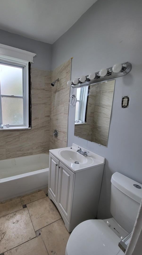 full bathroom with vanity, tiled shower / bath combo, and toilet