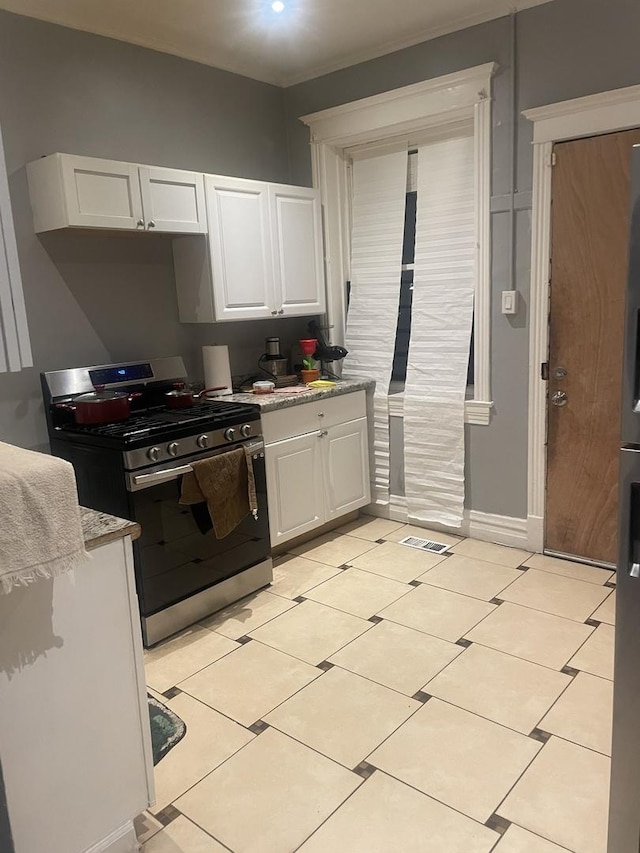 kitchen featuring white cabinets, light tile patterned flooring, and gas range