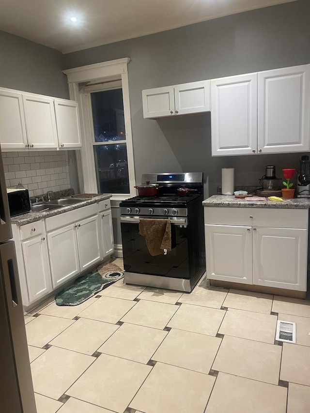 kitchen with white cabinets, appliances with stainless steel finishes, light tile patterned floors, and sink