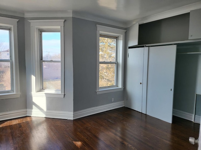 unfurnished bedroom featuring a closet, dark hardwood / wood-style floors, and ornamental molding