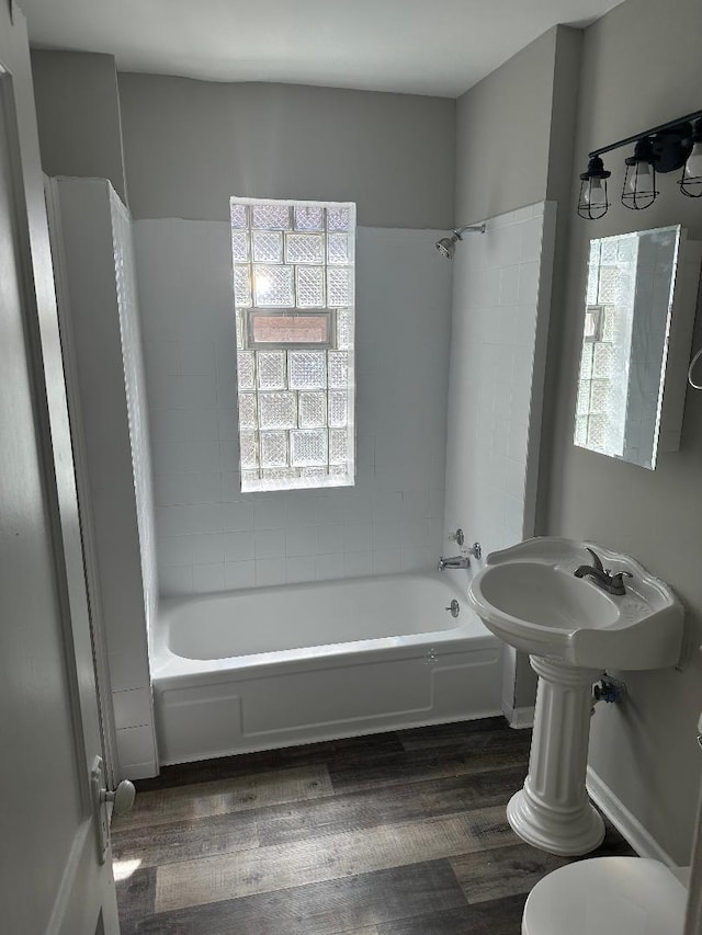 bathroom with hardwood / wood-style floors, tiled shower / bath combo, and toilet