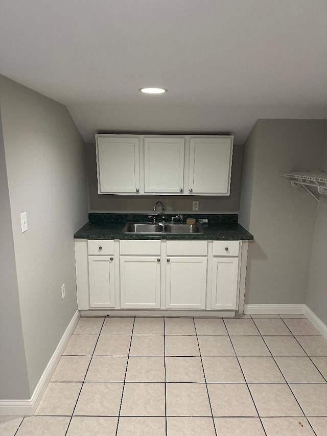 kitchen with white cabinets, light tile patterned floors, vaulted ceiling, and sink