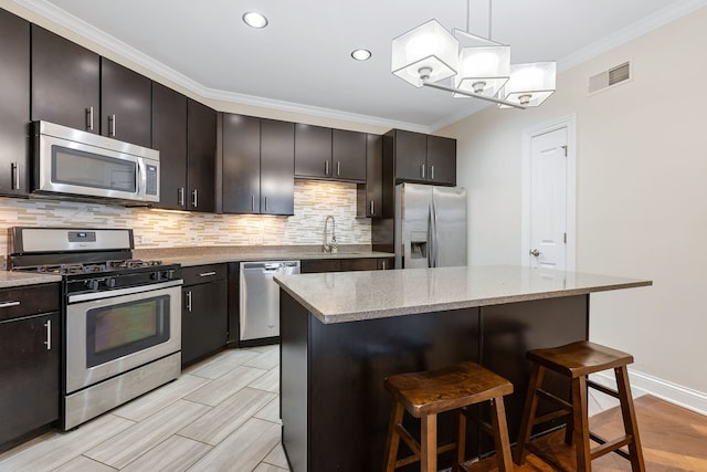 kitchen featuring dark brown cabinetry, pendant lighting, a breakfast bar, a kitchen island, and appliances with stainless steel finishes