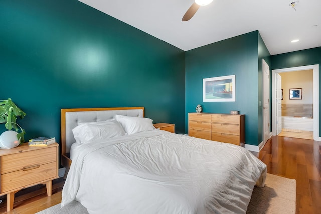 bedroom featuring ceiling fan, ensuite bathroom, and dark hardwood / wood-style floors