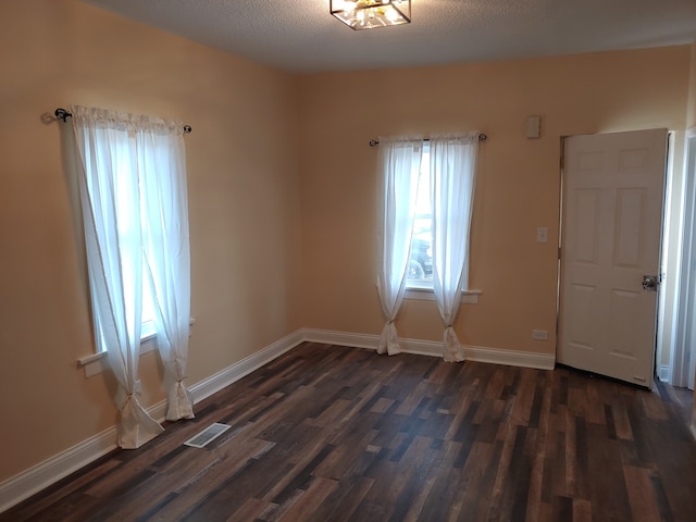 empty room with a textured ceiling and dark wood-type flooring